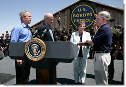 President George W. Bush stands with U.S.Homeland Security Secretary Michael Chertoff during the swearing-in ceremony of W. Ralph Basham, right, as the new Commissioner for U.S. Customs and Border Protection, Tuesday, June 6, 2006 at the Federal Law Enforcement Training Center Artesia Facility in Artesia, New Mexico. Commissioner Basham's wife, Judy Basham, holds the Bible during the ceremony.  White House photo by Eric Draper