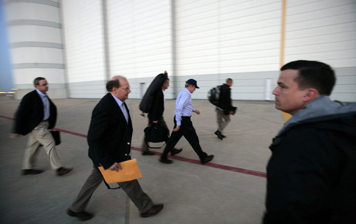 Accompanied by Dan Bartlett, left, Counselor to the President, and Deputy Chief of Staff Joe Hagin, President George W. Bush arrives at Andrews Air Force Base Monday night, June 12, 2006, en route to Iraq. White House photo by Eric Draper