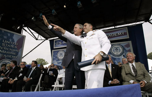 President George W. Bush waves to the audience with a recent graduate during the graduation ceremony at the United States Merchant Marine Academy at Kings Point, New York, Monday, June 19, 2006. White House photo by Kimberlee Hewitt