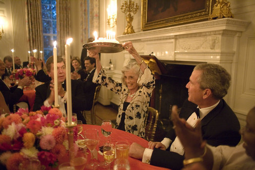 President George W. Bush watches Eunice Kennedy Shriver holding up a birthday cake during a dinner honoring her 85th birthday in the State Dining Room of the White House, Monday, July 10, 2006. Mrs. Shriver founded the Special Olympics in 1968. White House photo by Paul Morse