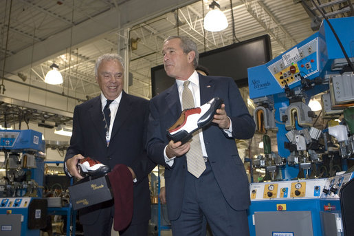 President George W. Bush holds up red, white and blue shoes presented to him by CEO John Stollenwerk during his visit to the Allen-Edmonds Shoe Corporation in Port Washington, Wis., Tuesday, July 11, 2006. White House photo by Kimberlee Hewitt