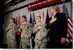 President George W. Bush recites the Pledge of Allegiance Monday, July 24, 2006, at Walter Reed Army Medical Center in Washington, D.C., joining newly sworn-in American citizens, Specialist Sergio Lopez, 24, of Bolingbrook, Ill., left, Specialist Noe Santos-Dilone of Brooklyn, N.Y., center, and Private First Class Eduardo Leal-Cardenas of Los Angeles, Calif., during their naturalization ceremony. White House photo by Eric Draper