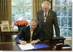 President George W. Bush is joined by U.S. Rep. Roscoe Bartlett, R- Md., as he signs H.R. 42, Freedom to Display the American Flag Act of 2005, Monday, July 24, 2006, in the Oval Office of the White House. The bill prevents a condominium association, cooperative association, or residential real estate management association from denying an owner or resident from displaying the U.S. flag on their residential property within the association. White House photo by Paul Morse