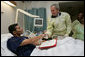 President George W. Bush awards a Purple Heart medal and citation to U.S. Marine Corps Stf. Sgt. Angel Barcenas of Paramount, Calif., Tuesday, Aug. 1, 2006, at the National Naval Medical Center in Bethesda, Md., as his family look on. Barcenas is recovering from wounds suffered in Operation Iraqi Freedom. White House photo by Eric Draper