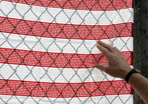 A visitor at the fence overlooking Ground Zero touches an American flag printed with names of those who were killed during the September 11th terrorist attacks Sunday, September 10, 2006. President and Mrs. Bush also visited the site Sunday to mark the fifth anniversary of the attacks. White House photo by Kimberlee Hewitt