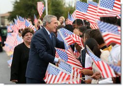 President George W. Bush reaches into a flurry of flags to greet students at George W. Bush Elementary School in Stockton, Calif., Tuesday, Oct. 3, 2006. White House photo by Eric Draper