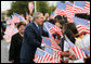 President George W. Bush reaches into a flurry of flags to greet students at George W. Bush Elementary School in Stockton, Calif., Tuesday, Oct. 3, 2006. White House photo by Eric Draper