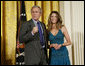 President George W. Bush joins singer Ana Cristina on stage to thank her and guitarist Marco Linares for their performance Friday, Oct. 6, 2006, in the East Room of the White House, in celebration of Hispanic Heritage Month. White House photo by Paul Morse