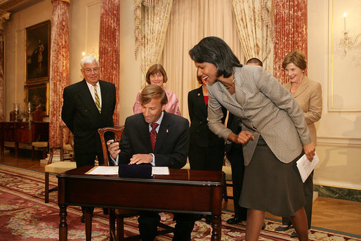 Mrs. Laura Bush, along with family of Ambassador Mark Dybul, watch as U.S. Secretary of State Condoleezza Rice assists newly sworn-in Ambassador Mark Dybul as he signs appointment documents Tuesday, October 10, 2006, during the swearing-in ceremony of Ambassador Mark Dybul in the Benjamin Franklin Room at the U.S. Department of State in Washington, D.C. White House photo by Shealah Craighead