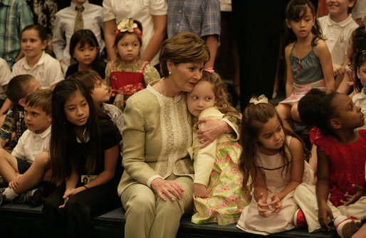 Mrs. Laura Bush hugs a little girl during a group photo with children of U.S. embassy staff during an embassy greeting in Singapore Thursday, November 16, 2006. White House photo by Eric Draper