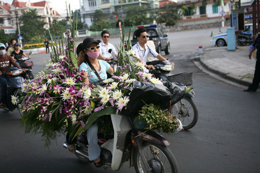 Vendors on mopeds carry flowers for sale early Saturday morning, Nov. 18, 2006, in Hanoi. White House photo by Paul Morse