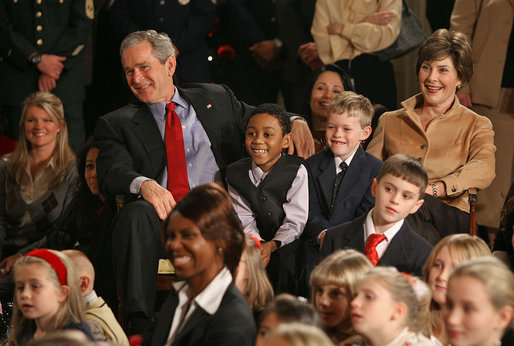 President George W. Bush and Mrs. Laura Bush sit with children of deployed U.S. military personnel and watch a performance of "Willy Wonka" by members of The Kennedy Center Education Department in the East Room Monday, Dec. 4, 2006. White House photo by Eric Draper