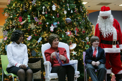 Mrs. Laura Bush sits with patient escorts Allison Meads, left, and Matthew Morgan, as she reads to an audience of children, patients and hospital staff Friday, Dec. 8, 2006, at The Children's National Medical Center in Washington, D.C., where Mrs. Bush visited with patients and debuted the 2006 Barney Cam video. White House photo by Shealah Craighead