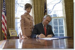 Laura Bush stands by President George W. Bush as he signs S. 843, the Combating Autism Act of 2006, in the Oval Office Tuesday, Dec. 19, 2006.  White House photo by Eric Draper