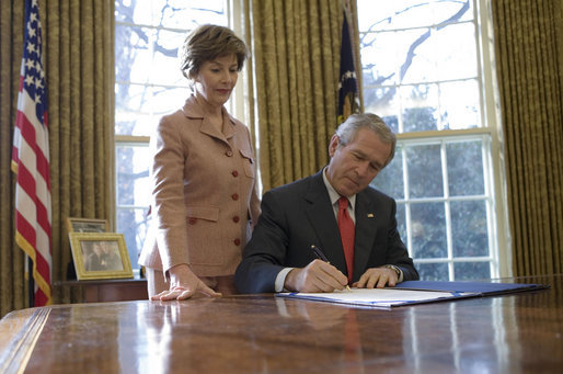 Laura Bush stands by President George W. Bush as he signs S. 843, the Combating Autism Act of 2006, in the Oval Office Tuesday, Dec. 19, 2006. White House photo by Eric Draper