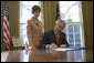 Laura Bush stands by President George W. Bush as he signs S. 843, the Combating Autism Act of 2006, in the Oval Office Tuesday, Dec. 19, 2006.  White House photo by Eric Draper