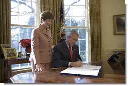 Laura Bush stands by President George W. Bush as he signs H.R. 6143, the Ryan White HIV/AIDS Treatment Modernization Act of 2006, in the Oval Office Tuesday, Dec. 19, 2006.  White House photo by Eric Draper