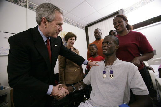 President George W. Bush shakes the hand of SSgt. Marcus Wilson after awarding him two Purple Hearts at the Walter Reed Army Medical Center in Washington, D.C., Friday, Dec. 22, 2006, as Mrs.Laura Bush and members of the Marine's family look on. Wilson, who is from Dermott, Arkansas, is recovering from wounds suffered in Operation Iraqi Freedom. White House photo by Eric Draper