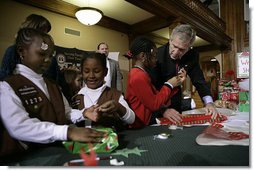 President George W. Bush helps young volunteers wrap presents for families of soldiers who were wounded in Iraq and Afghanistan, Friday, Dec. 22, 2006, at Walter Reed Army Medical Center in Washington, D.C.  White House photo by Eric Draper