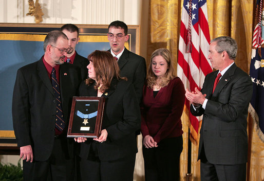 President George W. Bush presents the Medal of Honor to the family of Corporal Jason Dunham of the Marine Corps during a ceremony in the East Room Thursday, Jan. 11, 2007. The President spoke of Cpl. Dunham, "In April 2004, during an attack near Iraq's Syrian border, Corporal Dunham was assaulted by an insurgent who jumped out of a vehicle that was about to be searched. As Corporal Dunham wrestled the man to the ground, the insurgent rolled out a grenade he had been hiding. Corporal Dunham did not hesitate. He jumped on the grenade, using his helmet and body to absorb the blast. Although he survived the initial explosion, he did not survive his wounds. But by his selflessness, Corporal Dunham saved the lives of two of his men, and showed the world what it means to be a Marine." White House photo by Paul Morse
