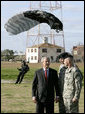 President George W. Bush speaks with U.S. Army Colonel Mike Linnington, center, and Sgt. 1st Class Mike Hertig, right, as he watches paratroopers from the U.S. Army Silver Wings Command exhibition team land Thursday, Jan. 11, 2006, during a demonstration of airborne infantry training at Fort Benning, Ga. White House photo by Eric Draper