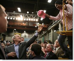 President George W. Bush reaches up to grab a worker’s cap to autograph it during his tour of the Caterpillar Inc. facility in East Peoria, Ill., Tuesday, Jan. 30, 2007.  White House photo by Paul Morse
