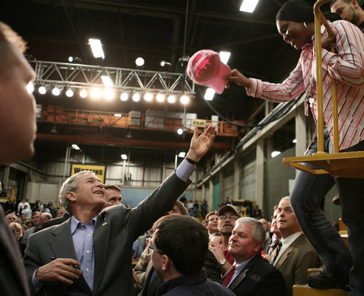 President George W. Bush reaches up to grab a worker’s cap to autograph it during his tour of the Caterpillar Inc. facility in East Peoria, Ill., Tuesday, Jan. 30, 2007. White House photo by Paul Morse