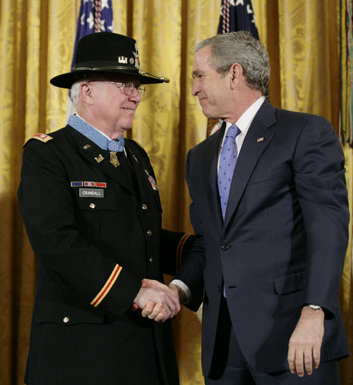 President George W. Bush shakes hands with U.S. Army Major Bruce P. Crandall after awarding Crandall the Medal of Honor in a ceremony in the East Room of the White House, Monday, Feb. 26, 2007, for his extraordinary heroism as a 1st Cavalry helicopter flight commander, completing 22 flights under intense enemy fire to aid troops in the Republic of Vietnam in November 1965. White House photo by Eric Draper