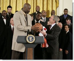 President George W. Bush receives an autographed ball from Shaquille O'Neal Tuesday, Feb. 27, 2007, as the 2006 NBA champions visited the White House. The President told the East Room audience he was most impressed by the Heat's work in their Miami community and added, "I mean, I'm in awe of their athletic skills. Standing next to Shaq is an awe-inspiring experience."  White House photo by Eric Draper