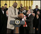 President George W. Bush receives an autographed ball from Shaquille O'Neal Tuesday, Feb. 27, 2007, as the 2006 NBA champions visited the White House. The President told the East Room audience he was most impressed by the Heat's work in their Miami community and added, "I mean, I'm in awe of their athletic skills. Standing next to Shaq is an awe-inspiring experience." White House photo by Eric Draper