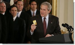 President George W. Bush holds up a card saying "15 Strong," this year's motto for the 2006 NBA champion Miami Heat, during the team's visit Tuesday, Feb. 27, 2007 to the White House. Said the President, "They had the stars. but it was the capacity to play together, to put the team ahead of themselves, that enabled them to be here at the White House."  White House photo by Paul Morse
