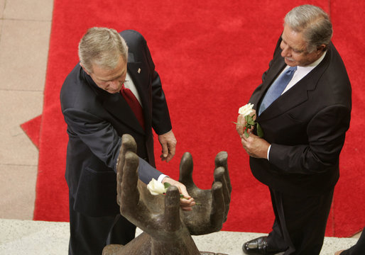 President George W. Bush lays a white rose in the palm of the Peace Statue as Guatemalan President Oscar Berger looks on Monday, March 12, 2007, at the Palacio Nacional de la Cultura in Guatemala City. White House photo by Paul Morse