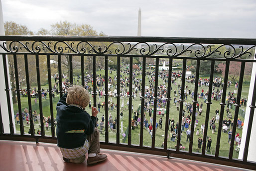 A young guest from the breakfast reception for the 2007 White House Easter Egg Roll peeks through the railing on the Truman Balcony for a birds-eye view of the activities on the South Lawn. White House photo by Shealah Craighead