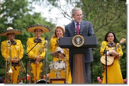 President George W. Bush welcomes guests to the Rose Garden at the White House Friday, May 4, 2007, to celebrate Cinco de Mayo and recognize the contributions of Mexican Americans. Members of the band Los Hermanos Mora Arriaga, who performed at the ceremony, are seen in background.  White House photo by Eric Draper