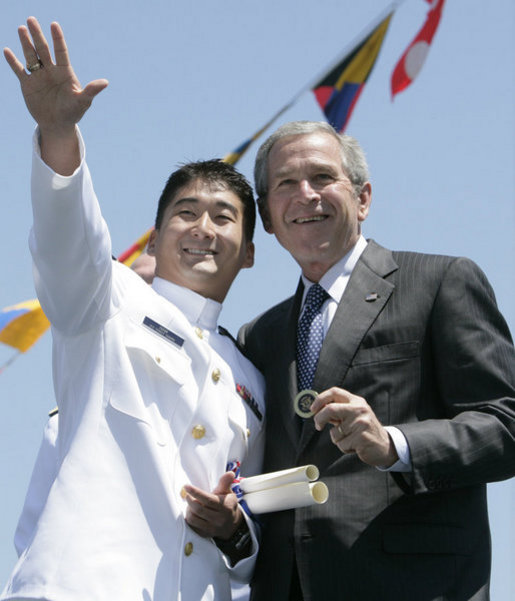 President George W. Bush holds a coin presented to him by U.S. Coast Guard graduate Daniel Kyung-Hyun Han, after President Bush presented him with his commission Wednesday, May 23, 2007, at the U.S. Coast Guard Academy commencement in New London, Conn. White House photo by Joyce Boghosian