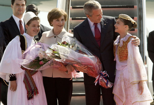 Mrs. Laura Bush holds flowers presented to her by Sara Shehu, 12, and Frensis Spaho, 13, upon the arrival Sunday, June 10, 2007, of she and President George W. Bush to Albania. The visit marked the first by a sitting U.S. president to the country. White House photo by Chris Greenberg