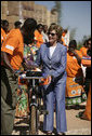 Mrs. Laura Bush loads a home care kit onto a bicycle at the Mututa Memorial Center Thursday, June 28, 2007, in Lusaka, Zambia. The center, which promotes abstinence and faith for youth, provides many humanitarian services including home-based care for people living with HIV/AIDS and care for orphans. It serves more than 150 individuals with a core of 36 trained caregivers. White House photo by Shealah Craighead
