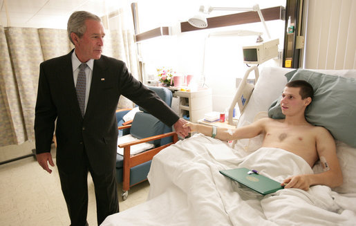 President George W. Bush reaches back for the hand of Army National Guard Spec. Dave Saucier, of Sabattus, Me., after he honored the soldier with a Purple Heart Tuesday, July 3, 2007, during a visit to Walter Reed Army Medical Center. White House photo by Eric Draper