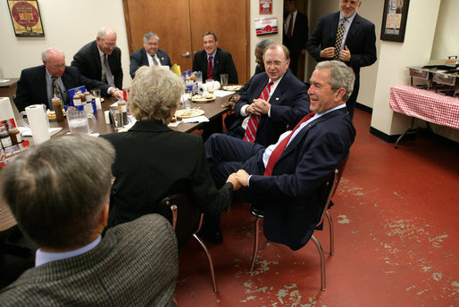 President George W. Bush participates in a lunch meeting with local business and civic leaders at the Whole Hog Cafe in Rogers, Ark., Monday, Oct. 15, 2007, speaking with Susan Barrett, left, president of Mercy Health System of Northwest Arkansas, Inc., and John A. White, Jr., chancellor of the University of Arkansas, right. White House photo by Eric Draper