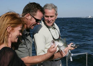 President George W. Bush is shown a fish caught by Melissa Fischer, left, by her husband, Chris Fischer, aboard a fishing boat Saturday, Oct. 20, 2007 off the coast of St. Michaels, Md., in the Chesapeake Bay, during a television interview with the Fischers, hosts of ESPN’s Offshore Adventures. President Bush talked about his love of the outdoors and the Executive Order signed earlier in the day to protect striped bass and red drum fish species. White House photo by Eric Draper