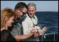President George W. Bush is shown a fish caught by Melissa Fischer, left, by her husband, Chris Fischer, aboard a fishing boat Saturday, Oct. 20, 2007 off the coast of St. Michaels, Md., in the Chesapeake Bay, during a television interview with the Fischers, hosts of ESPN’s Offshore Adventures. President Bush talked about his love of the outdoors and the Executive Order signed earlier in the day to protect striped bass and red drum fish species. White House photo by Eric Draper