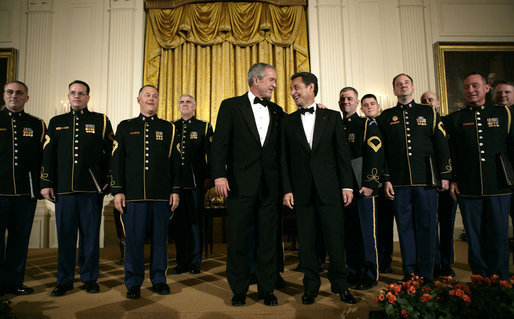 President George W. Bush and President Nicolas Sarkozy of France stand on stage with the Army Chorus in the East Room of the White House Tuesday, Nov. 6, 2007, following the after-dinner performance by the 22-member group. White House photo by Eric Draper