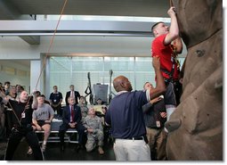 President George W. Bush, left, watches as double amputee Lance Cpl. Matt Bradford, who is also blind, climbs a wall, during President Bush’s visit Thursday, Nov. 8, 2007 to the physical therapy and training area for wounded soldiers at the Center for The Intrepid at the Brooke Army Medical Center in San Antonio, Texas. White House photo by Eric Draper