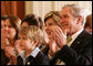 President George W. Bush and Mrs. Laura Bush are joined by Elijah Atkins, Friday, Nov. 16, 2007 in the East Room of the White House, as they listen to Atkins' father, country music star Rodney Atkins, performing for guests during the celebration of National Adoption Day. Rodney Atkins is the 2007-2008 national celebrity spokesperson for The National Council for Adoption. White House photo by Chris Greenberg