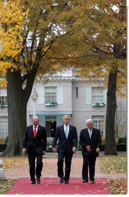 President George W. Bush is flanked by Prime Minister Ehud Olmert, left, of Israel, and President Mahmoud Abbas of the Palestinian Authority as they walk Tuesday, Nov. 27, 2007, from the Buchanan House on the grounds of the U.S. Naval Academy in Annapolis, Maryland, to Bancroft Hall during the Annapolis Conference. The leaders agreed to immediately resume Mideast peace talks.  White House photo by Chris Greenberg