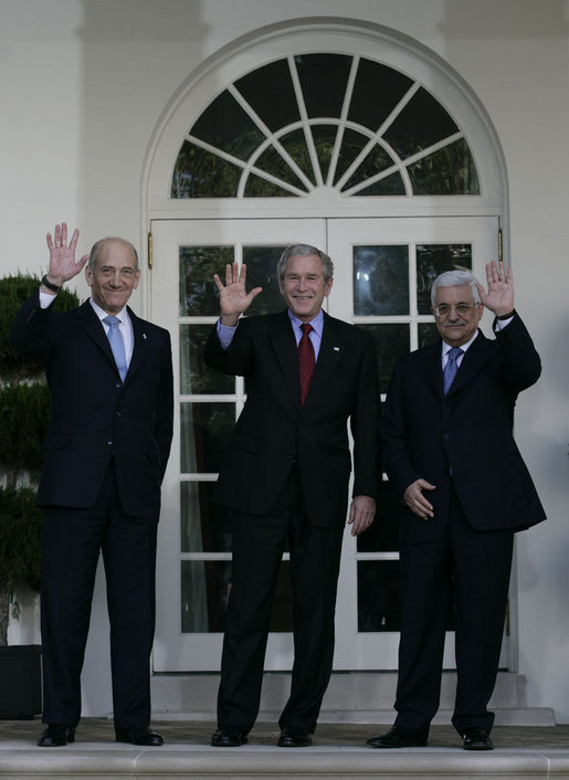 President George W. Bush is flanked by Prime Minister Ehud Olmert, left, of Israel, and President Mahmoud Abbas of the Palestinian Authority, as they wave for the cameras Wednesday, Nov. 28, 2007, after a statement in the Rose Garden regarding the Annapolis Conference. White House photo by Eric Draper