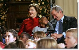 President George W. Bush and Mrs. Laura Bush share a moment with Malik Lawson during the Children's Holiday Performance Monday, Dec. 3, 2007, at the White House. The 7-year-old is the son of Sgt. Sherry Martin, currently serving in Iraq.  White House photo by Joyce N. Boghosian