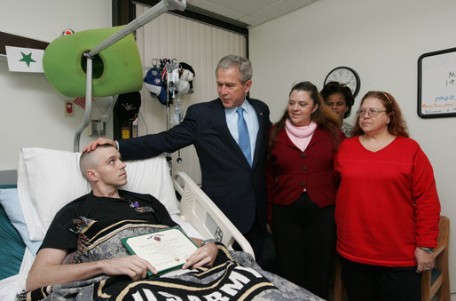 President George W. Bush visits with U.S. Army Sgt. John Wayne Cornell of Lansing, Mich., after presenting him with a Purple Heart Thursday, Dec. 20, 2007, during a visit to Walter Reed Army Medical Center in Washington, D.C., where he is recovering from injuries suffered in Operation Iraqi Freedom. With them are Sgt. Cornell's wife, Dee, and mother-in-law Diane Elaine Galloway. White House photo by Joyce N. Boghosian