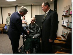 President George W. Bush presents the Purple Heart to U.S. Army Spc. John C. Hoxie of Philippi, W.Va., during a visit Thursday, Dec. 20, 2007, to Walter Reed Army Medical Center in Washington, D.C., where the soldier is recovering from injuries suffered in Operation Iraqi Freedom. Looking on is the soldier's father, David Hoxie. White House photo by Joyce N. Boghosian