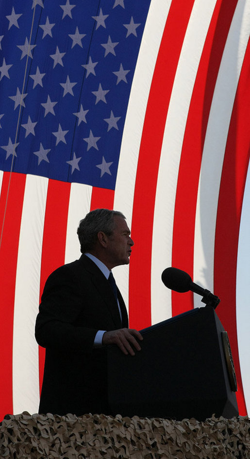 President George W. Bush stands in front of a U.S. flag Saturday, Jan. 12, 2008, as he addresses military personnel and coalition forces at Camp Arifjan in Kuwait. The President told the troops, "It's hard work you're doing, but it's necessary work." White House photo by Eric Draper